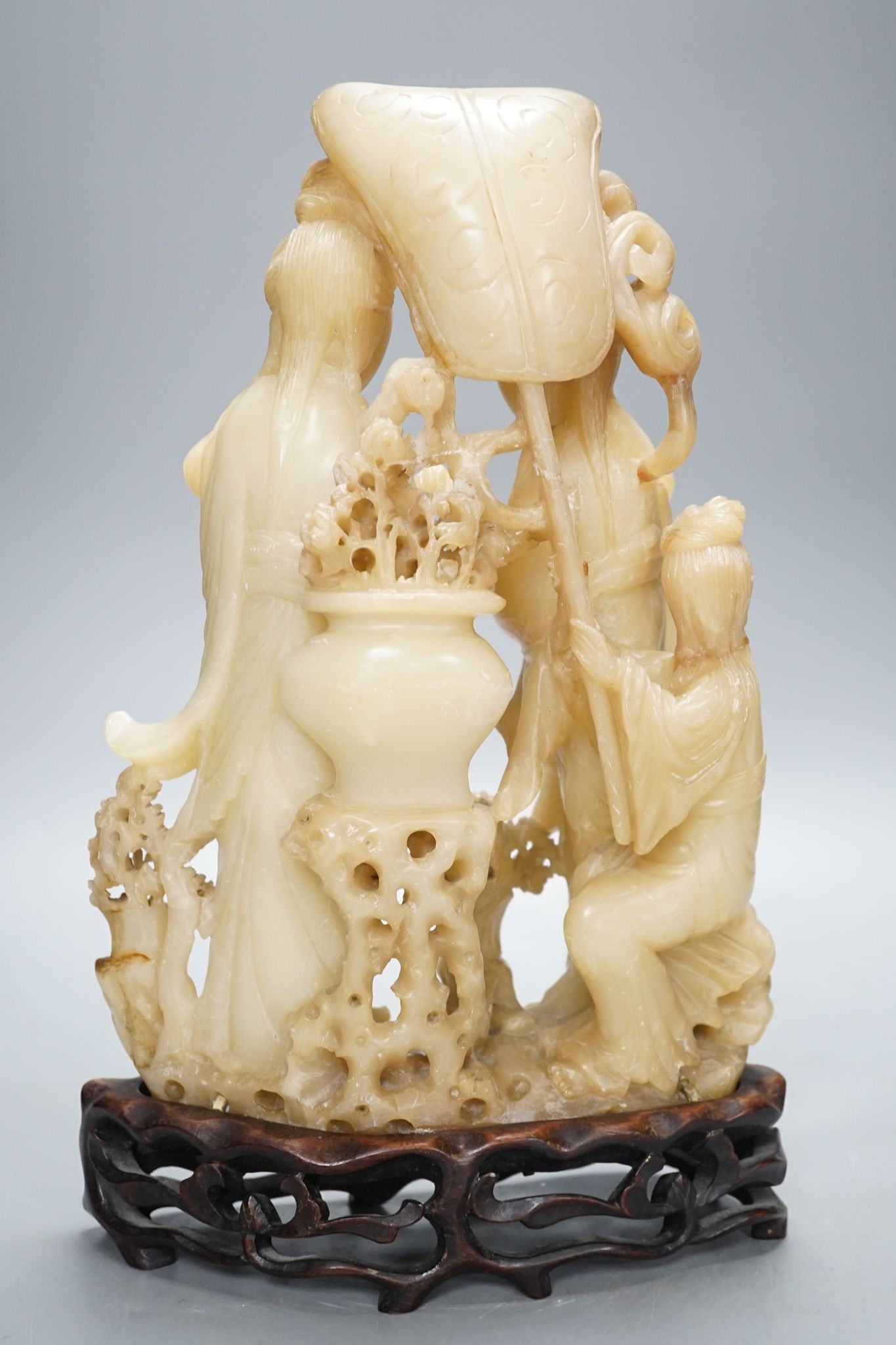 A Chinese soapstone carving of two ladies, wood stand, early 20th century, 36 cms high.